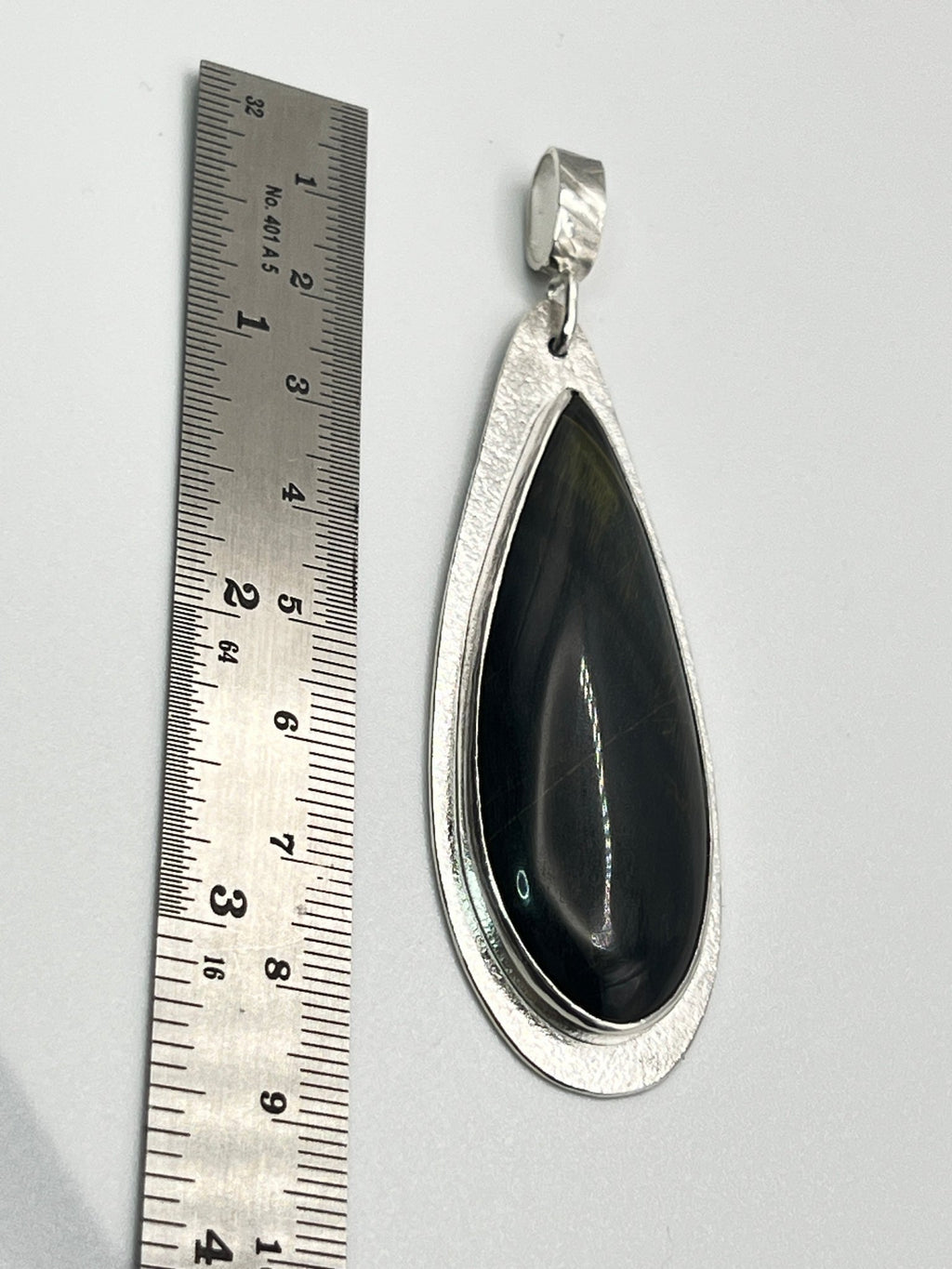 Size reference photo of handmade blue tiger eye sterling silver statement pendant next to ruler.