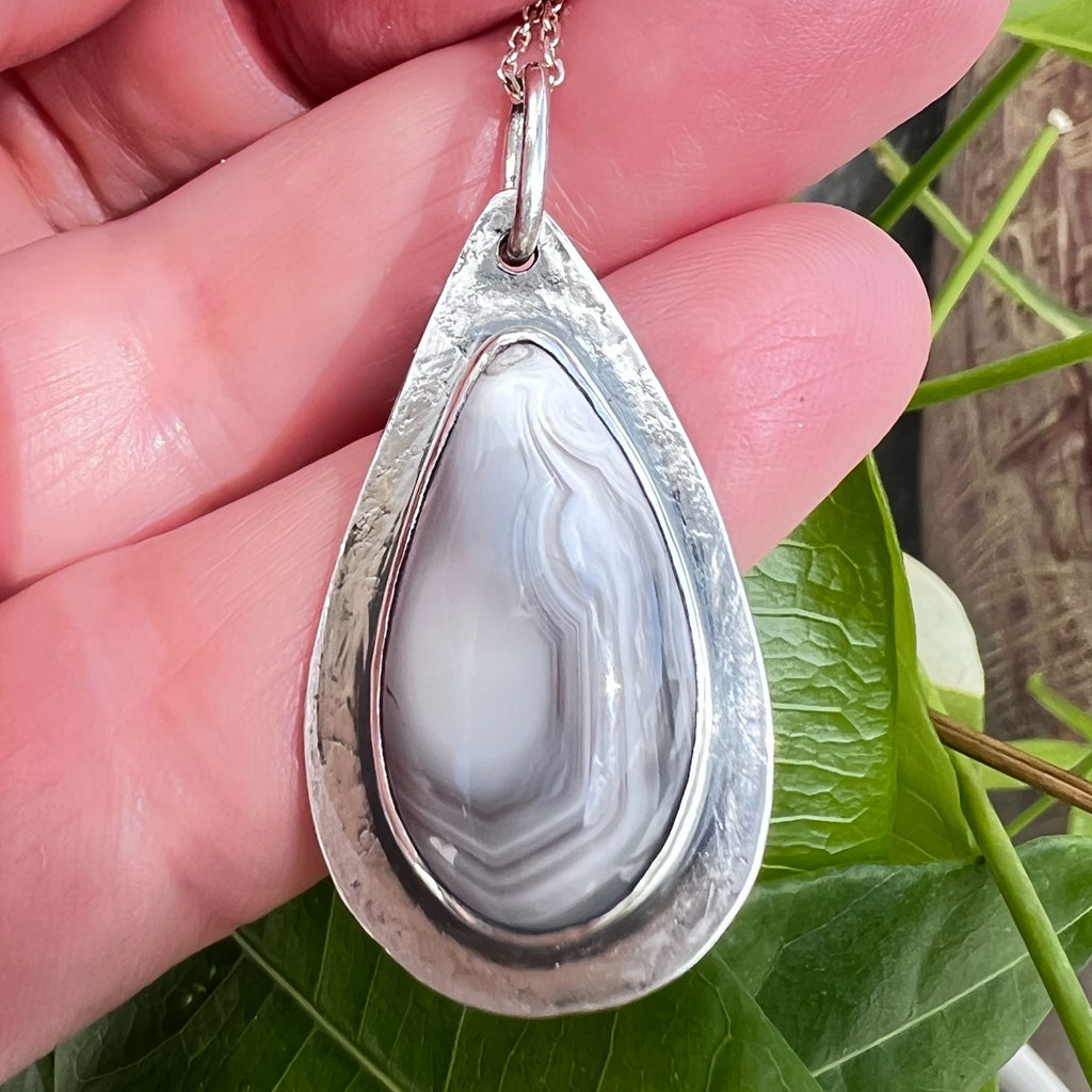 Nature inspired, minimalist sterling silver pendant with natural agate gemstone, laying on the hands where you can see its approximate size