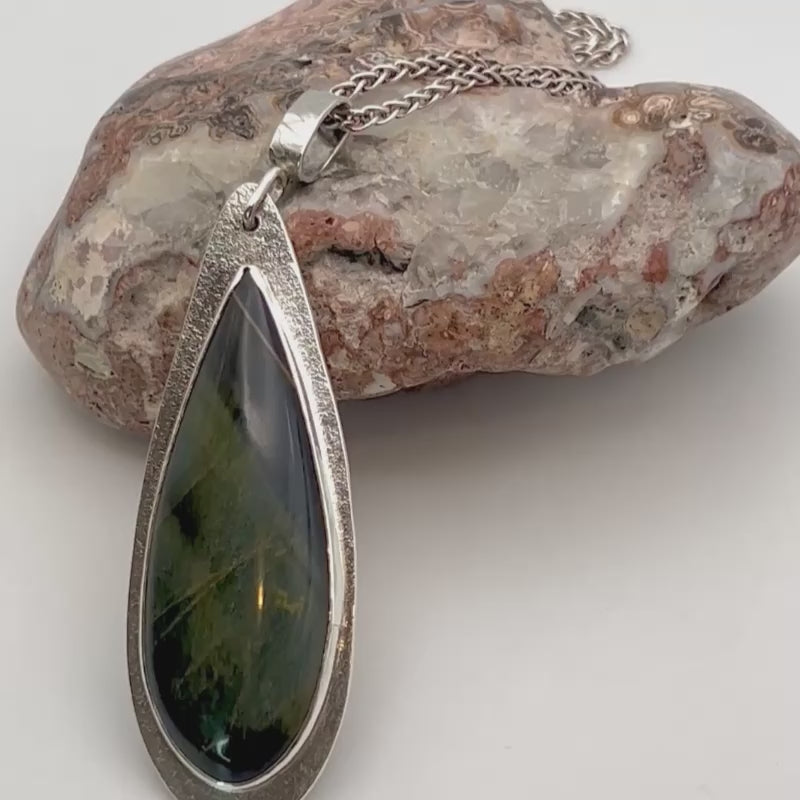 Blue tiger eye statement penant video. Laying on the stone